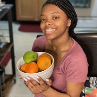 A woman holding a bowl of fruit in her hands.